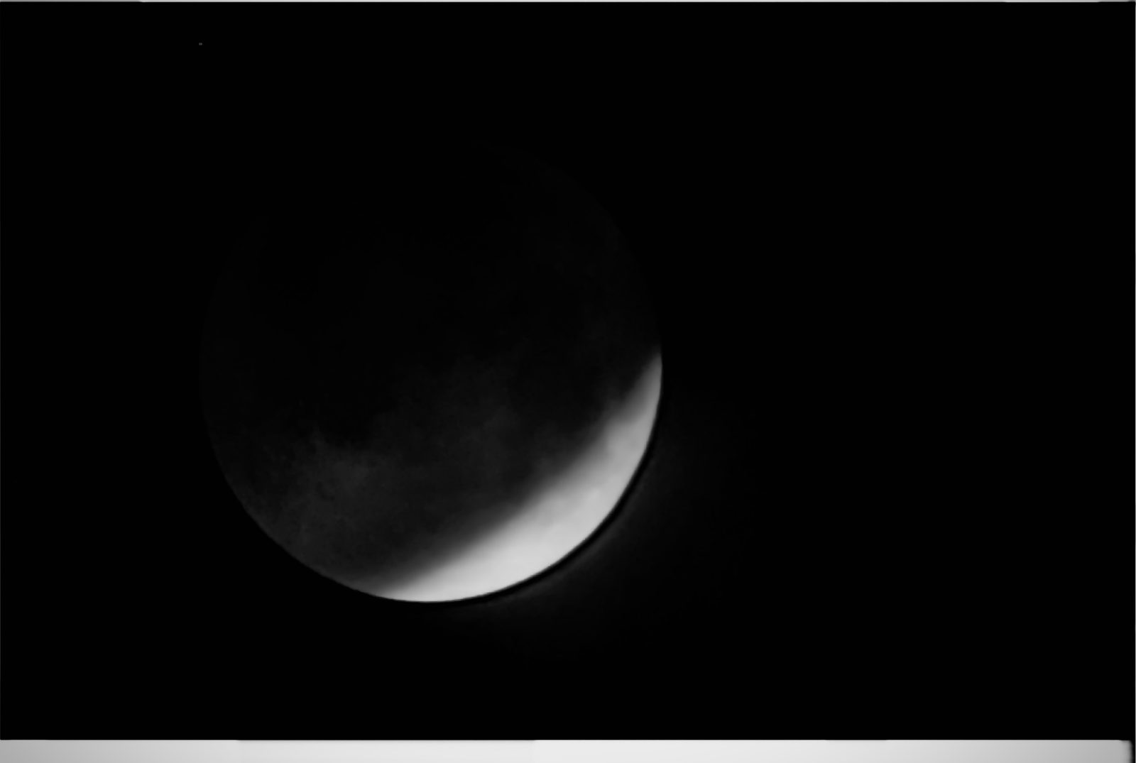 A crescent moon, most of its face in shadow, against a black sky